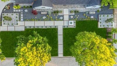 Aerial view of a Russwood Acres Dallas, TX front yard with concrete walkways, green lawn, gravel beds, Corten steel planters, and structured plantings