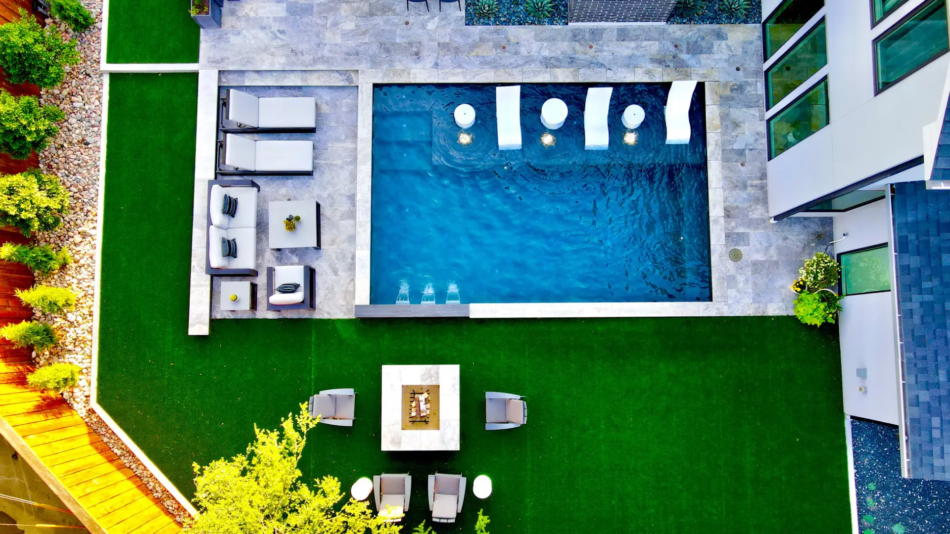 Aerial view of a modern backyard pool, fire feature, lounge seating, and artificial turf in a Dallas, Texas outdoor living space