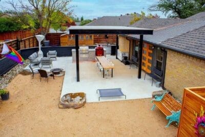 Covered outdoor living patio in Prestonwood Dallas, TX with dining table, grill station, fire pit seating, decomposed granite, and wood privacy fencing
