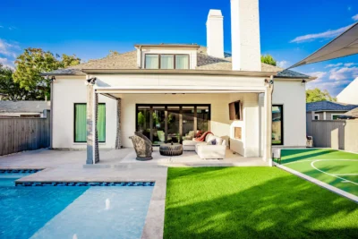 Modern backyard outdoor living space with pool, covered patio, turf lawn, sport court, shade structure, and lounge seating in Midway Hollow Dallas, Texas.